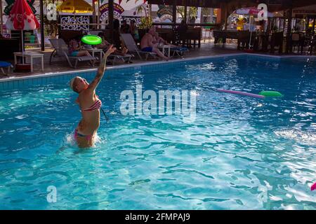 08-12-2015 Ayia Napa, Cyprus. Young woman (blonde) plays Dog Frisbee at the hotel pool in Ayia Napa - amazing August Stock Photo
