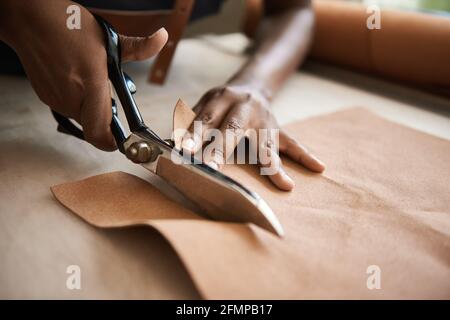 African female artisan cutting leather in her workshop Stock Photo