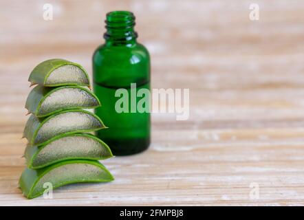 A small green bottle with a dropper and Cut Aloe Vera leaves close up Stock Photo
