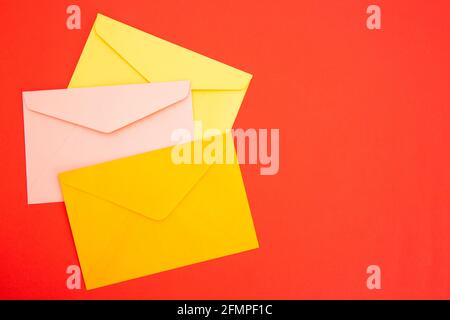 Colorful paper envelopes on red background - top view Stock Photo