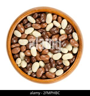 Roasted soybeans, coated with chocolate, in a wooden bowl. Snack of crispy roasted soybeans, covered with dark, milk and white chocolate. Close-up. Stock Photo