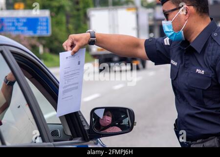 Kuala Lumpur, Malaysia. 11th May, 2021. A policeman checks passing vehicles as part of the Movement Control Order to curb the COVID-19 pandemic on a high way connecting Selangor and Kuala Lumpur, in Petaling Jaya, Malaysia, May 11, 2021. Malaysia recorded 3,973 new cases of COVID-19, bringing the total tally to 448,457, the Health Ministry said on Tuesday. Credit: Chong Voon Chung/Xinhua/Alamy Live News Stock Photo