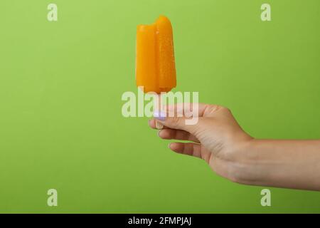 Female hand hold ice cream stick on green background Stock Photo