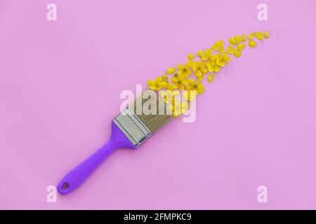 Creative layout with paint brush and yellow wild flowers on pink background. Brush paints with flowers. Copy space Stock Photo