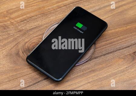 smartphone battery charging showing half charged battery on fast wireless charger concept Stock Photo