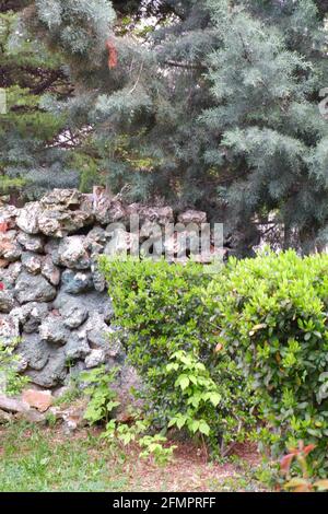 Decorative masonry stone wall at park within bushes Stock Photo