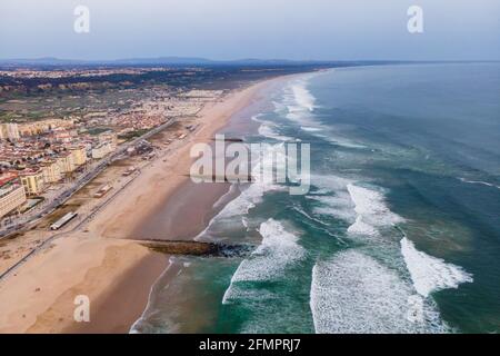 Aerial view of Costa da Caparica landscape at sunset, view of the majestic beach with rough Atlantic Ocean rolling on the shoreline, Setubal, Portugal Stock Photo