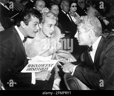 Husband and Wife TONY CURTIS and JANET LEIGH talking to JEFF CHANDLER at the Hollywood premiere of Jane Wyman and Rock Hudson in MAGNIFICENT OBSESSION in July 1954 with OTTO KRUGER in background publicity for Universal International Pictures (UI) Stock Photo