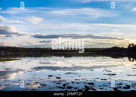 Tranquil scene with white clouds and sky reflected in calm sea at high tide in winter sunlight. Red Wharf Bay, Isle of Anglesey, Wales, UK, Britain Stock Photo