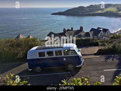 An old Volkswagen split screen camper van being used as a wedding vehicle makes it's way up the hill at Langland Bay near Swansea, UK. Stock Photo