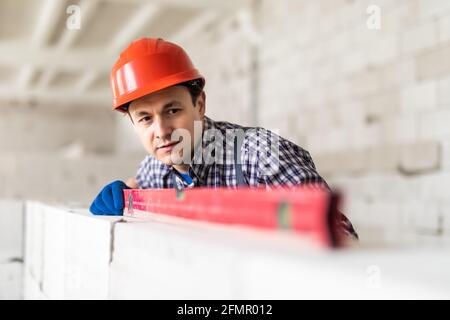 Construction worker observing and surveying wall alignment using water ...