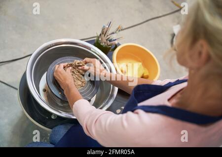 Make something unique. High angle view of woman shaping, creating handmade clay ceramics in pottery workshop studio Stock Photo