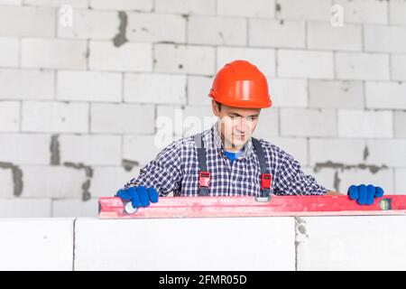 Building worker measuring the wall with a water level at construction site. Stock Photo
