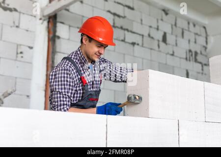 Bricklayer installing wall from autoclaved aerated concrete blocks Stock Photo