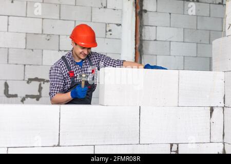 bricklayer man builder working with autoclaved aerated concrete blocks. Walling Stock Photo