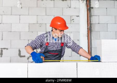 bricklayer man builder working with autoclaved aerated concrete blocks. Walling Stock Photo