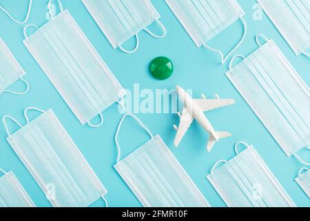 The plane is surrounded by medical masks on a blue background with a green dot of the destination. The concept of opening borders and freedom of movem Stock Photo