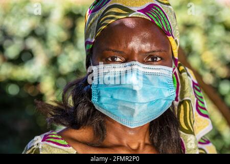 African middle aged woman, female in Africa, wearing traditional clothes and face mask in Coronavirus COVID-19 pandemic Stock Photo