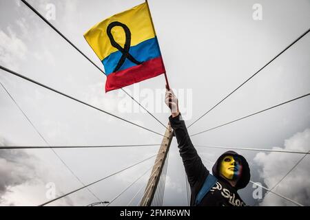 FILED - 06 May 2021, Colombia, Pereira: A protester wearing a mask in the colors of the Colombian flag waves a flag with a black ribbon during a rally for demonstrator Lucas Villa, who was seriously injured during a protest against the government. The 37-year-old yoga teacher was reportedly hit by eight bullets during the protest, according to local media reports. On May 11, it was informed, Villa succumbed to his injuries. According to information from the national ombudsman's office, a total of more than 25 people are said to have died during the protest days. (to dpa 'Symbol of the protests Stock Photo