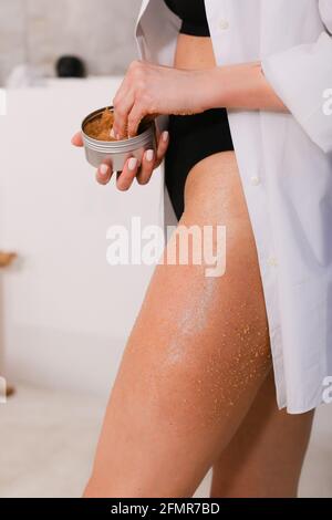 Woman applying nourishing scrub on body on bathroom background, closeup Stock Photo
