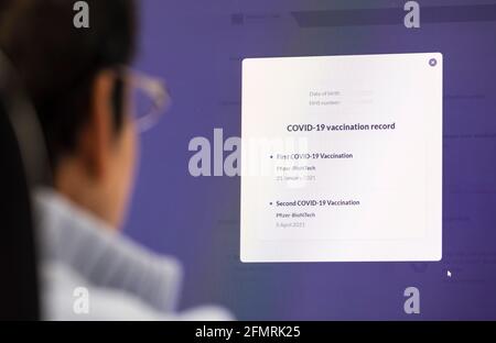 BUCKINGHAMSHIRE, UK - May 01, 2021. Covid 19 vaccine record. British Asian Indian woman checking her Covid-19 vaccination record on an NHS Primary Car Stock Photo