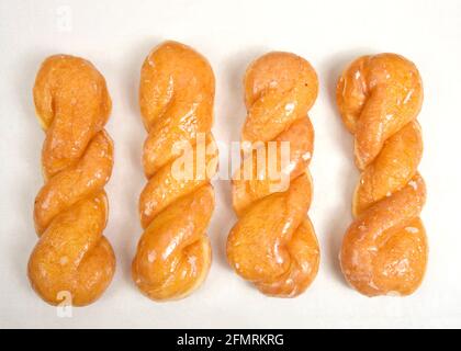 Flat lay top view of glazed twist donuts on parchment paper. Stock Photo