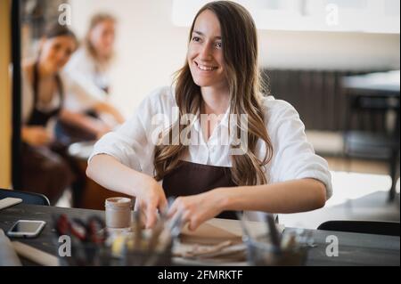Young women learning to sculpt with a clay during a lesson at workshop in art studio Stock Photo