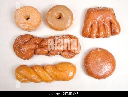 Flat lay top view of variety of specialty donuts. Glazed twists, cinnamon twist, jelly filled, bear claw, sugar coated and maple donuts. Stock Photo