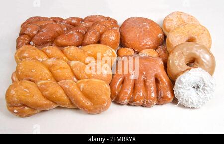 Variety of donuts arranged on parchment paper clustered together. Bear Claw, glazed twists, Cinnamon Twist, jelly filled, sugar coated, coconut covere Stock Photo