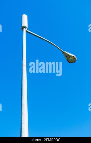 Looking up on a typical small cell antenna for 5G wireless network installed on a street light pole. Blue sky