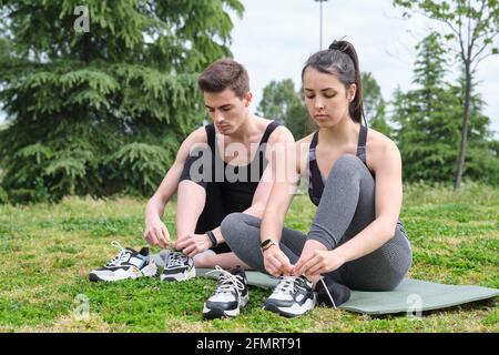 Two friends putting on and lacing or tying their trainers. Sport outside. Stock Photo