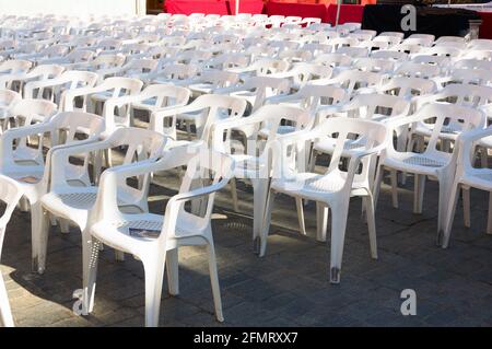 Perspective of some white plastic chairs in which the public that comes to the venue to witness an outdoor show must sit Stock Photo