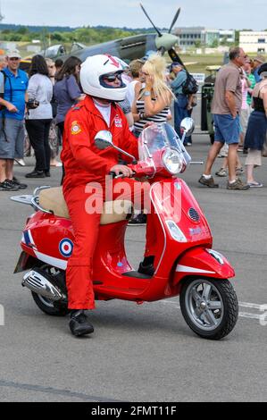 Royal Air Force Red Arrows pilot Mike Ling on a Red Arrows painted Vespa scooter at Farnborough International Airshow 2010, UK. Humorous ride Stock Photo