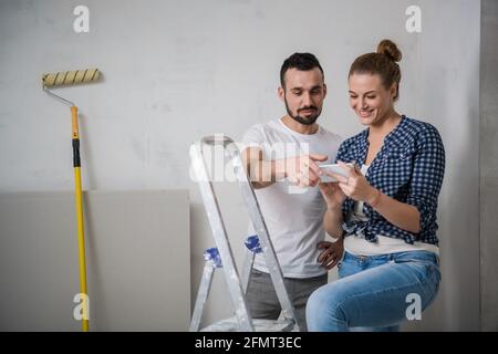 Man and woman looks at photos on the mobile phone screen. They take a break from renovation Stock Photo