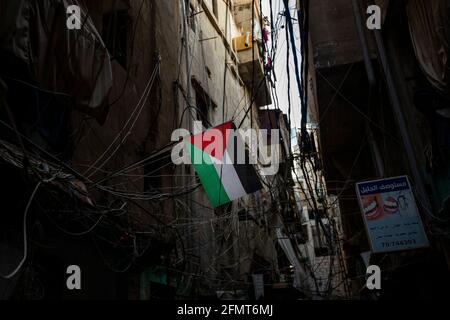May 11, 2021, Beirut, Beirut, Lebanon: A Palestinian flag hangs from a wall in the Shatilah Palestinian refugee camp as demonstrators marched beneath to show solidarity with Palestinians living in JerusalemÃs Sheikh Jarrah neighborhood in Beirut, Lebanon on May 11, 2021. The demonstrators marched from BeirutÃs Mar Elias Palestinian Refugee Camp to Shatilah Palestinian Refugee Camp to show solidarity with Palestinians living in JerusalemÃs Sheikh Jarrah, where Israeli settlers are attempting to forcibly steal several Palestinian familiesÃ homes. Palestinians in Jerusalem have protested the Stock Photo