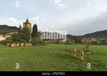 Typical Catalan countryside, rural grass with your mower, straw waltz and the church, surrounded by mountains. Stock Photo