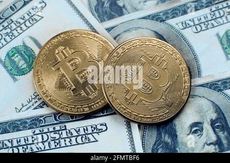Two coins of bitcoin cryptocurrency lie on one hundred dollar bills Stock Photo