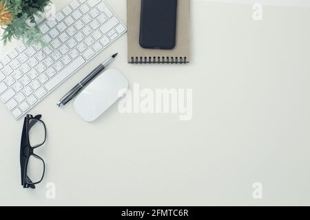 White keyboard mouse glasses pen notepad phone flower in pot on white background Stock Photo