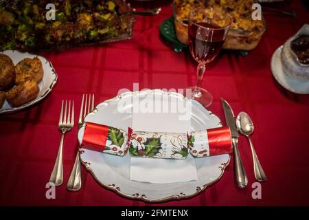 Christmas cracker on plate with red wine on Christmas dinner table Stock Photo