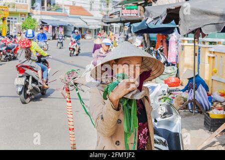 Close up portrait of middle aged Vietnamese trader wearing conical hat and carrying shoulder pole, Hoi An, Vietnam Stock Photo