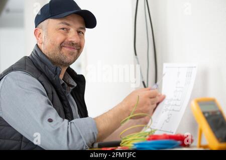 male electrician checking voltage of socket with multimeter in house Stock Photo