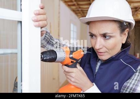 a woman using drilling machine Stock Photo
