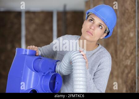 female electrician installing ventilation in ceiling Stock Photo