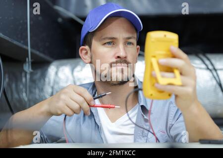 male technician repairing industrial air conditioner indoors Stock Photo