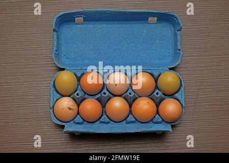 Ten fresh organic chicken eggs inside open box on wooden table Stock Photo