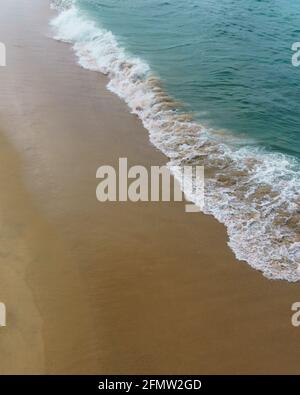 Areal view of ocean wave washing up onto sandy beach Stock Photo