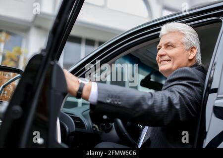 Senior businessman getting out of modern car Stock Photo