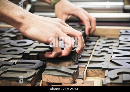 printing press handmade artisans letterpress hands placing wooden types on grid Stock Photo