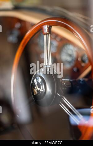 Shiny Wooden Steering Wheel and blur dashboard through car's window with reflection inside vintage 1960s Alvis Classic Car, New Zealand Stock Photo
