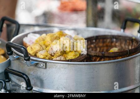 Dim Sum or Chinese dumpling in a stream hot pot of food wheelbarrow on street food of Bangkok. Many dumpling in a wooden basket is streaming in old As Stock Photo